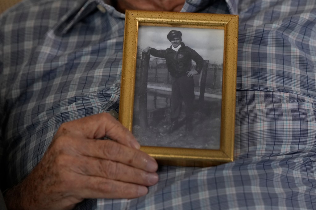 Harold Terens holding a photo of himself during WWII when he was 20, in Boca Raton. He will be honored by France as part of D-Day's 80th anniversary.