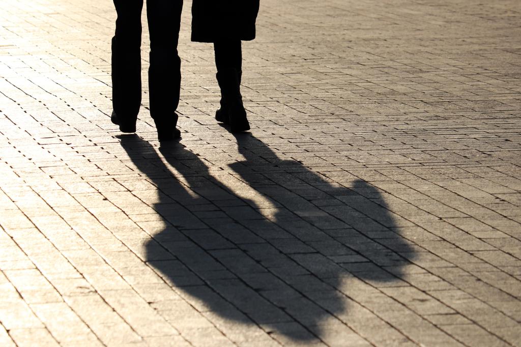 Silhouettes and shadows of couple walking down the street. People on a sidewalk, concept of relationship, family, dramatic life story