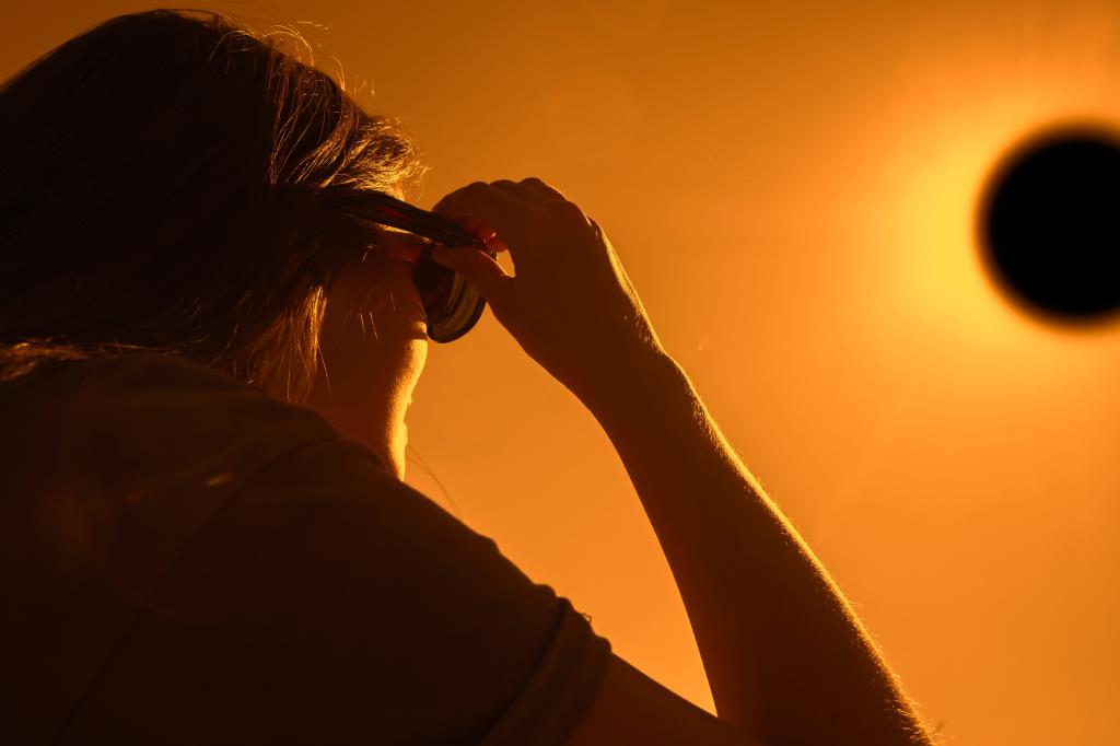 Woman is looking on solar eclipse through three sunglasses. Sun eclipse concept.