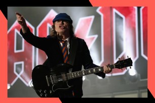 AC/DC guitarist Angus Young points to the crowd with his guitar in hand.