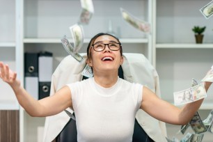 A woman throws her money in the air in excitement.