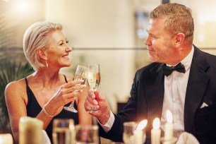 An older couple drinks champagne together at a dinner party.
