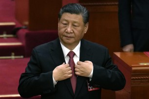 Chinese President Xi Jinping adjusts his jacket during the closing session of the National People's Congress.