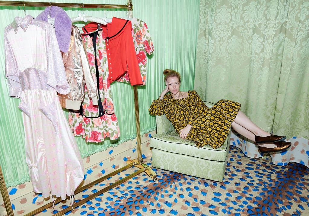 A woman lying on a chair in a room with clothes on a rack at the Batsheva Store