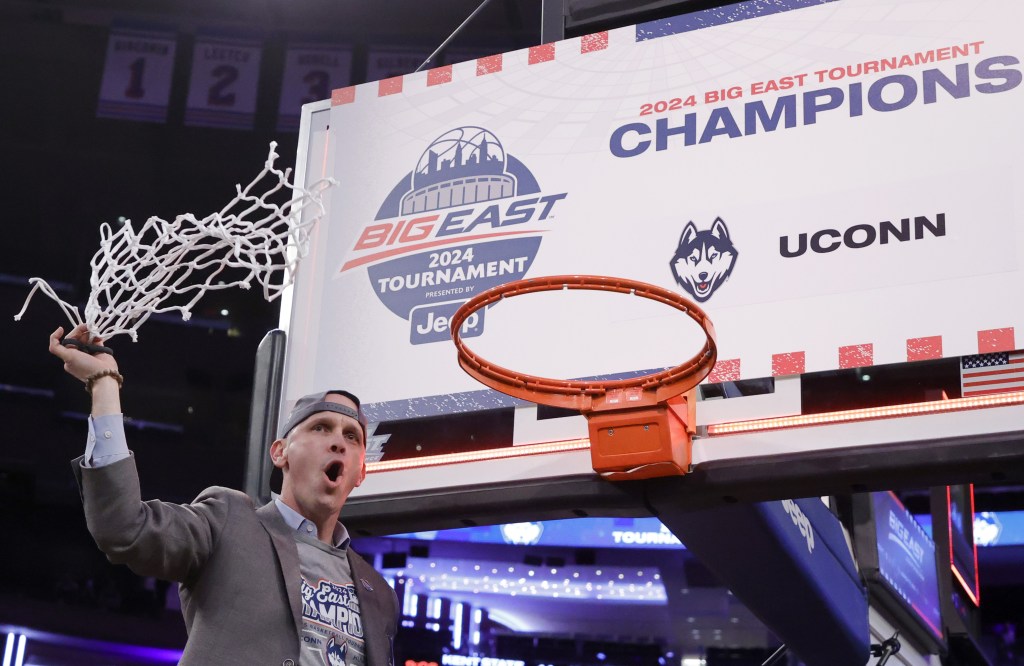 Dan Hurley celebrates after cutting the last string of the net after UConn's Big East Tournament-clinching win over Marquette.