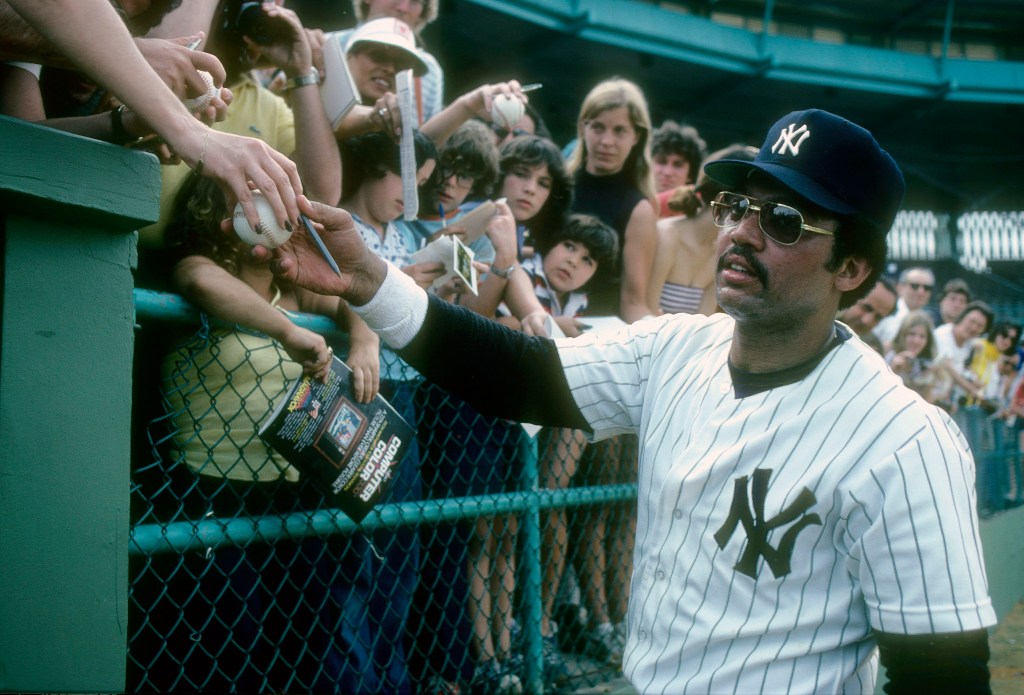 Outfielder Reggie Jackson #44 of the New York Yankees signs autographs for fans during a spring training game in 1980 in Tampa, Florida.