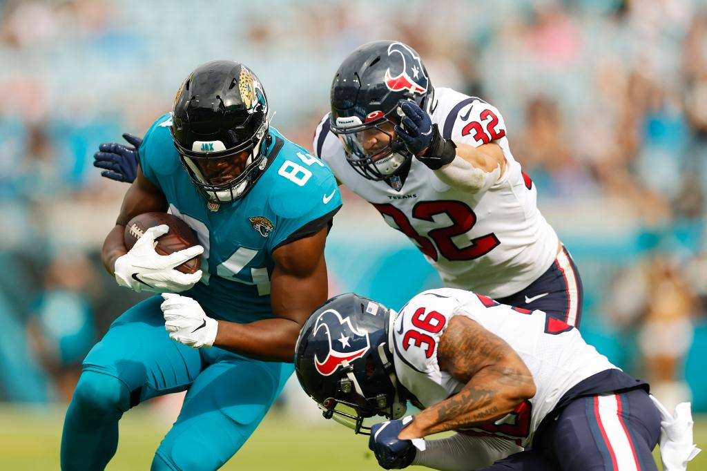 Chris Manhertz is tackled by Jonathan Owens #36 and Garret Wallow #32 of the Houston Texans during the first quarter at TIAA Bank Field.