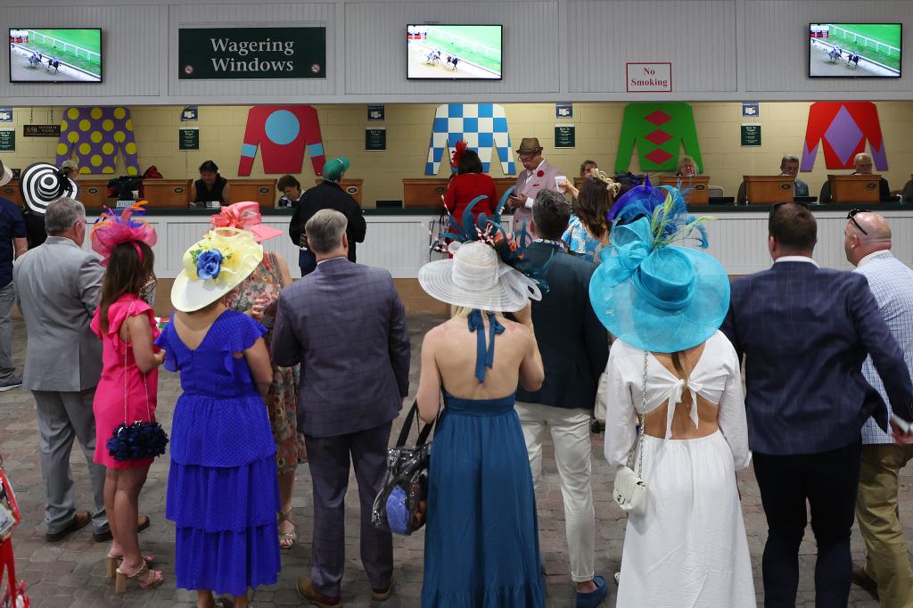 Spectators wait in line to wager on races prior to the 149th running of the Kentucky Derby at Churchill Downs.