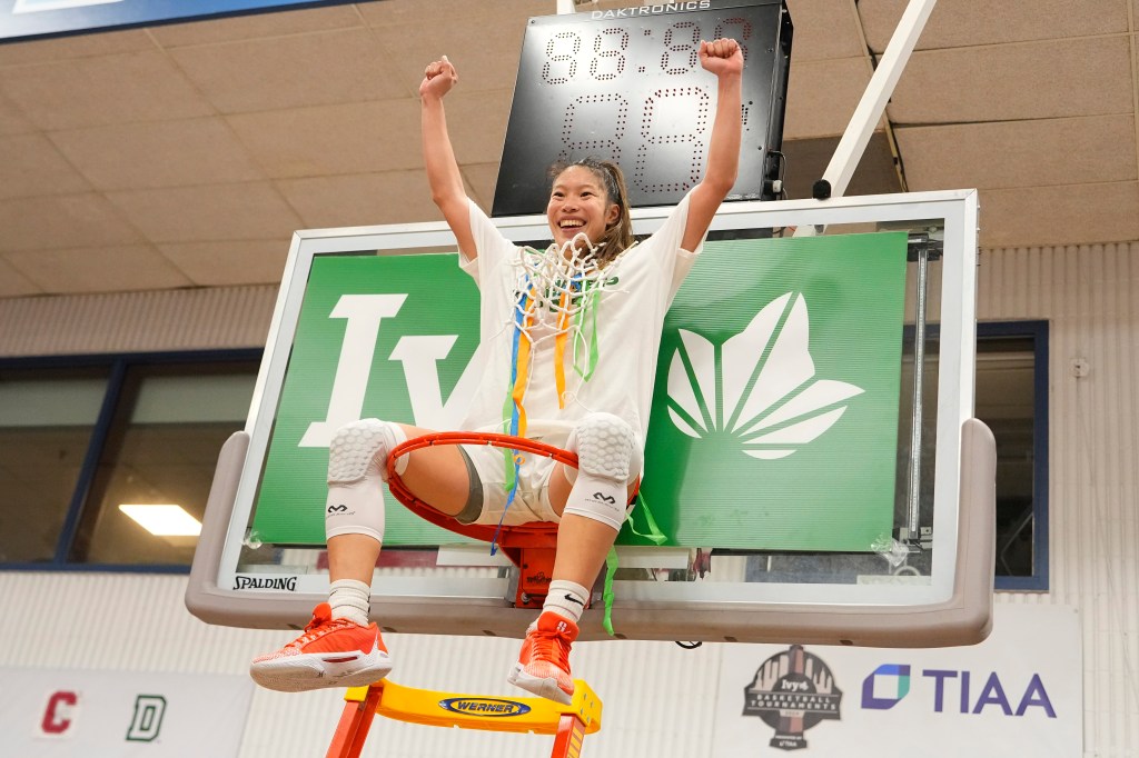 Princeton Tigers Guard Kaitlyn Chen (20) celebrates the victory by sitting on the basketball ring with the net after the Women's Ivy League League Basketball Championship game.