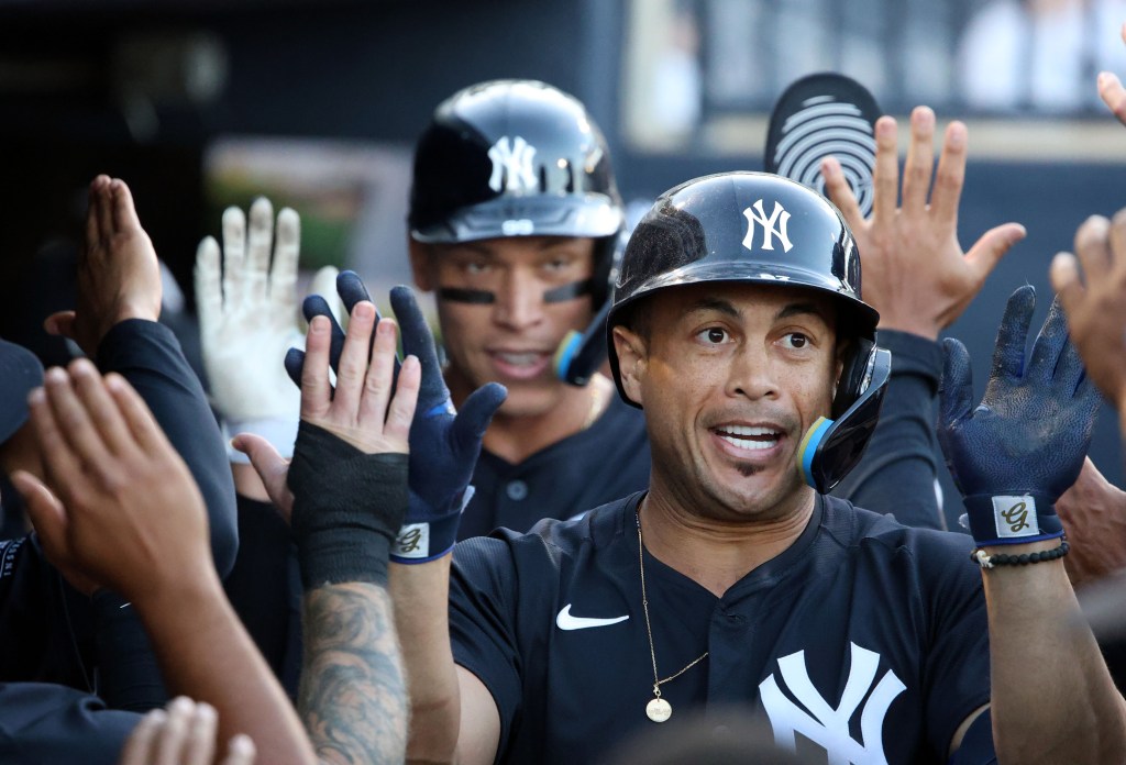 Giancarlo Stanton celebrates in the dugout with teammates after hitting one of his three homers in the Yankees' exhibition win over the Pirates.