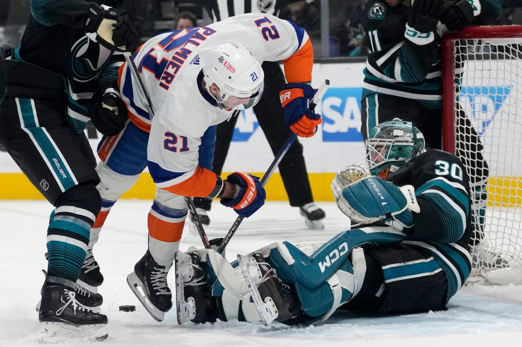 New York Islanders center Kyle Palmieri (21) falls forward in front of San Jose Sharks goaltender Magnus Chrona (30) during the second period of an NHL hockey game in San Jose, Calif., Thursday, March 7, 2024.