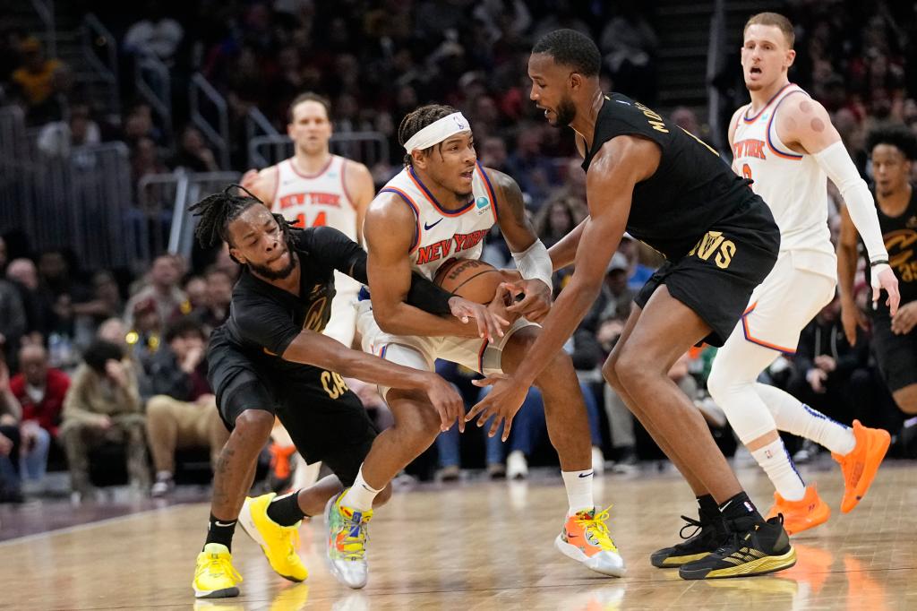 Cleveland Cavaliers guard Darius Garland (10) left, and forward Evan Mobley, right, pressure New York Knicks guard Miles McBride, center, in the second half of an NBA basketball game, Sunday, March 3, 2024, in Cleveland.