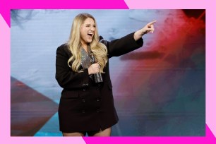 Meghan Trainor smiles wide while gesturing to the crowd.