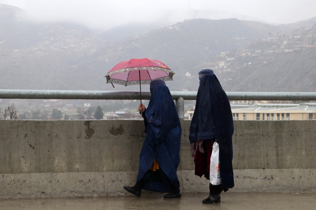 Afghan women walk along a road during a rainfall in Fayzabad, Badakhshan province, on March 21, 2024. 