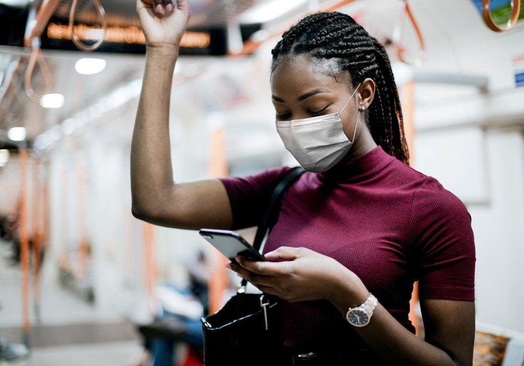 African American woman wearing mask on the bus while using public transportation.