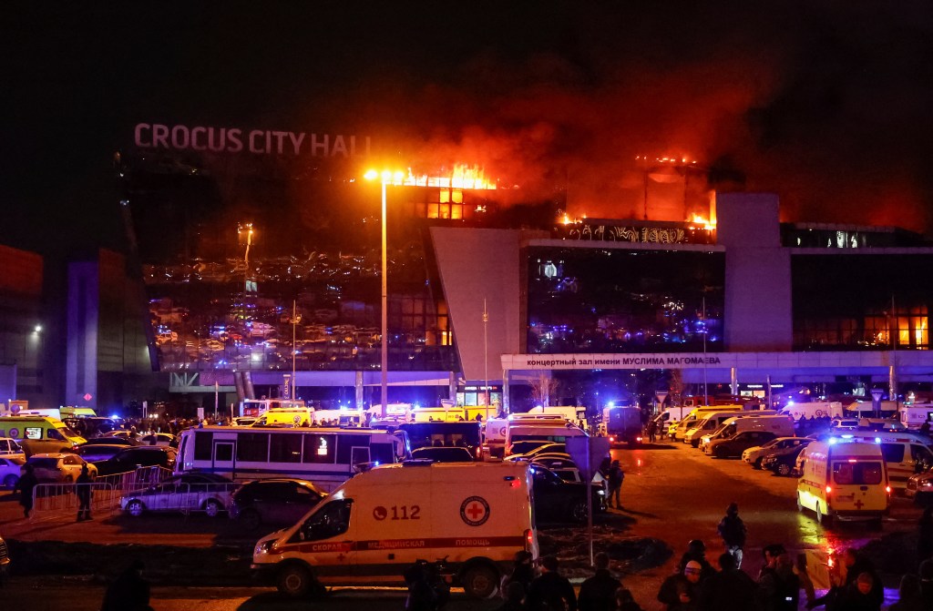 Ambulances and vehicles of Russian emergency services are parked at the burning Crocus City Hall concert venue following a shooting incident, outside Moscow, Russia