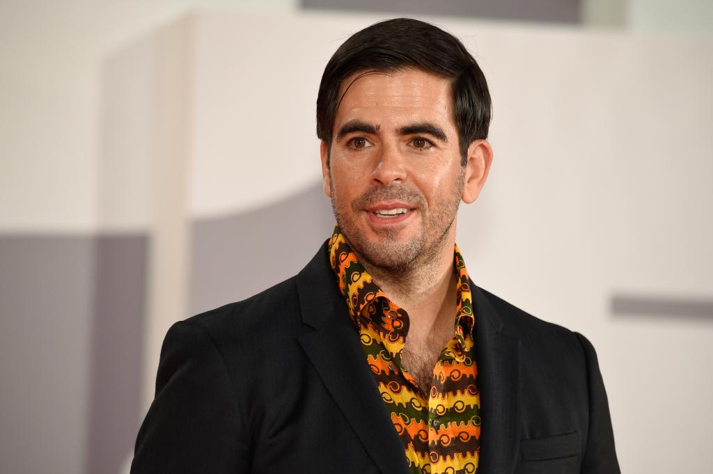 Eli Roth poses at the Venice Film Festival 2021 in a multi-colored shirt and black jacket.