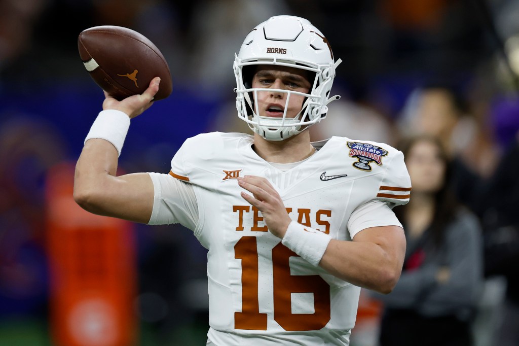 Arch Manning of the Texas Longhorns in football uniform holding a football, warming up before CFP Semifinal Allstate Sugar Bowl matchup in New Orleans.