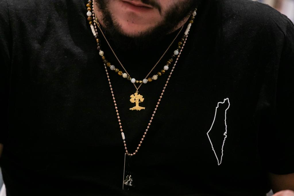 Aviad Mor Yosef a close up of his black t-shirt with a white outline on it, along with three necklaces.