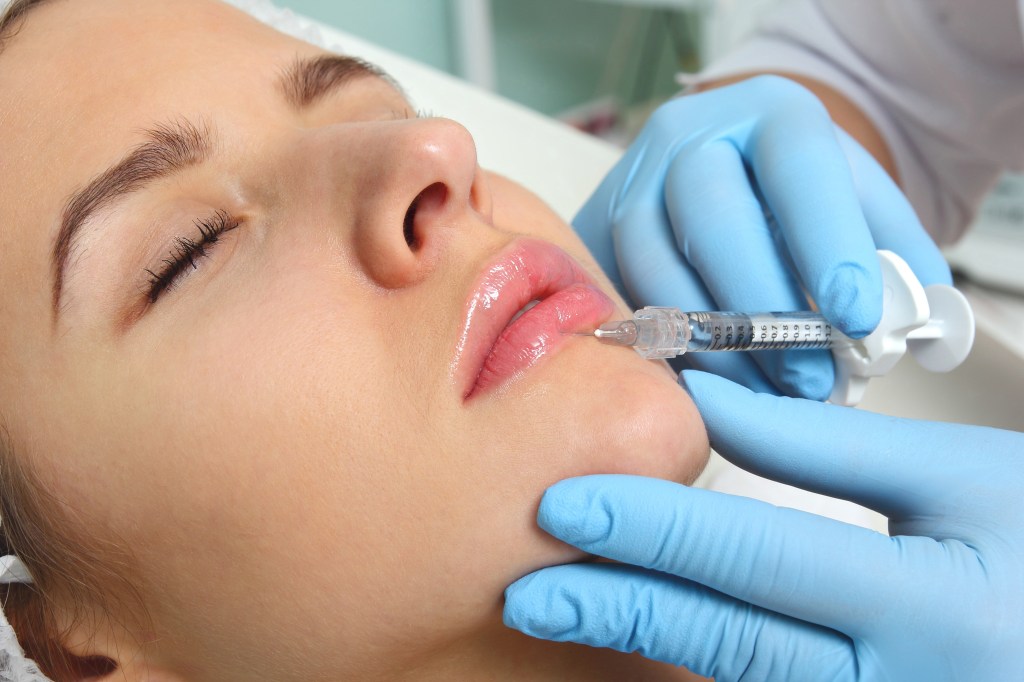 A woman getting a lip injection during a beauty procedure at a clinic.