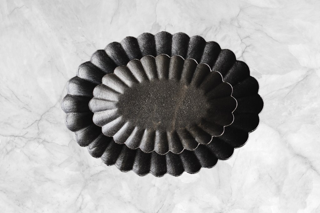 A stack of black oval shaped baking pans