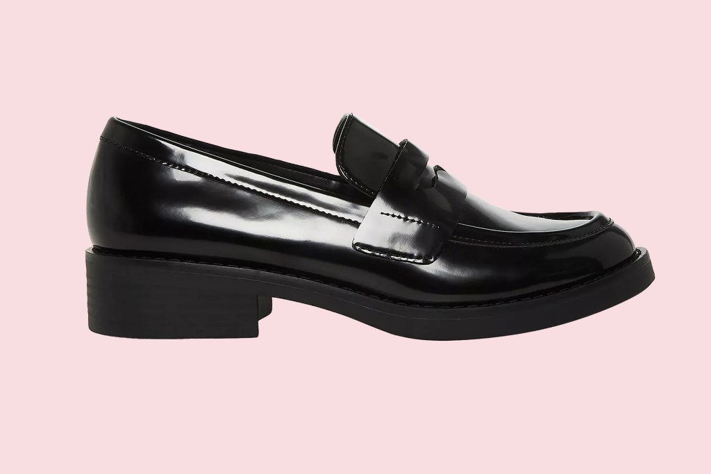 A black loafer on a pink background