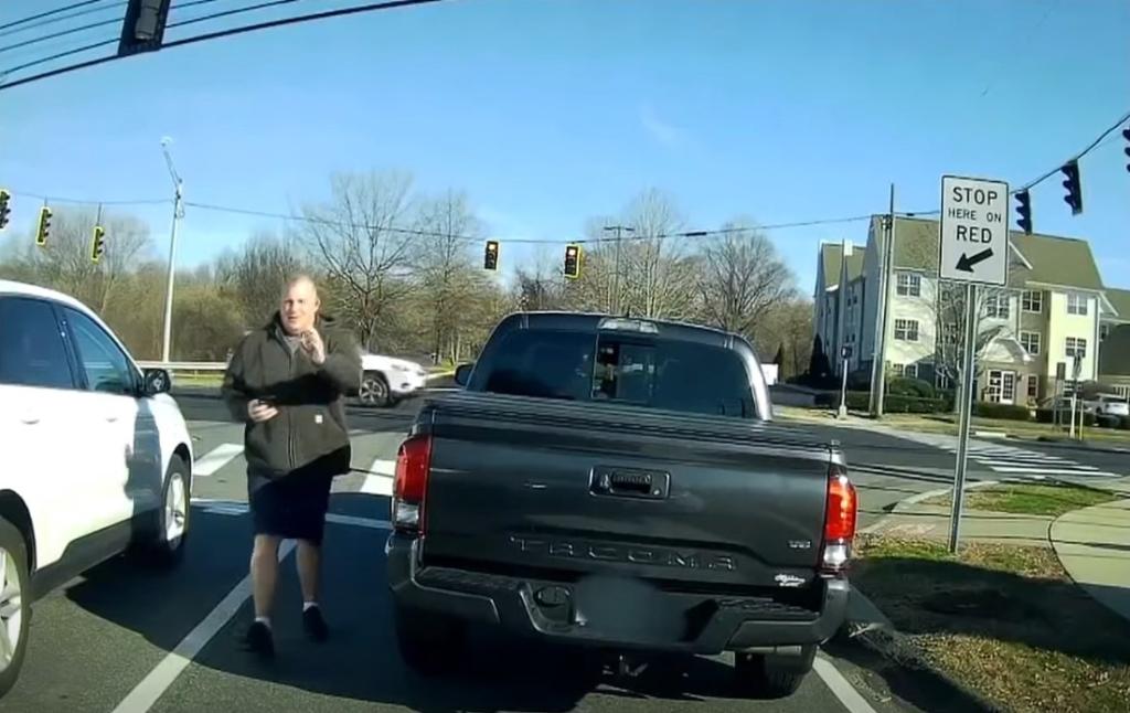 Meriden Police Department off-duty cop Allen Ganter is seen exiting his truck and waving his badge after being honked at for not turning right on red.