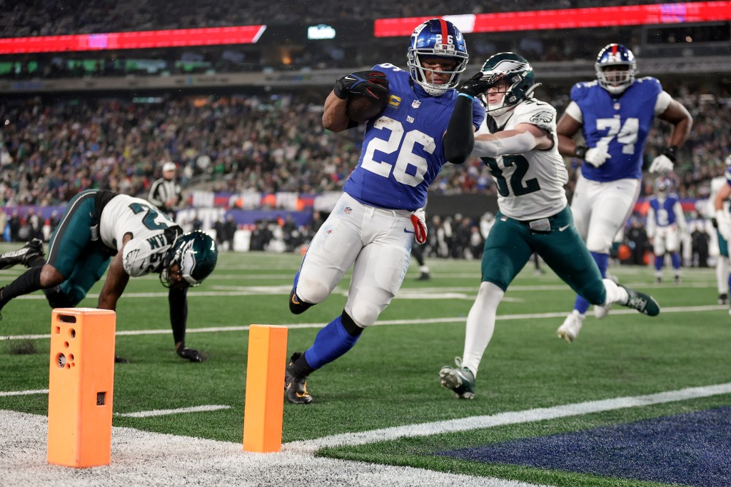 Giants running back Saquon Barkley (26) carries the ball into the end zone for a touchdown against Philadelphia Eagles safety Reed Blankenship (32) during the second quarter.