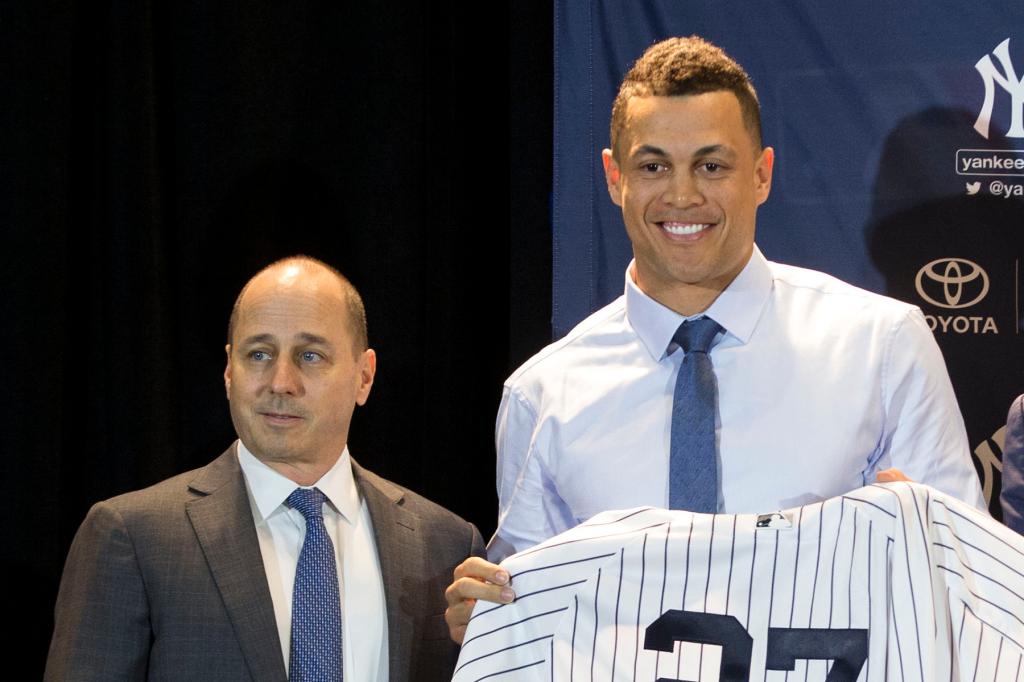 Yankees General Manager Brian Cashman, left, stands next to new Yankee Giancarlo Stanton, center, and his new jersey with Yankee Manager Aaron Boone, right middle, and Yankee Owner Hal Steinbrenner, right, during the Major League Baseball winter meetings in Orlando, Fla., Monday, Dec. 11, 2017. 