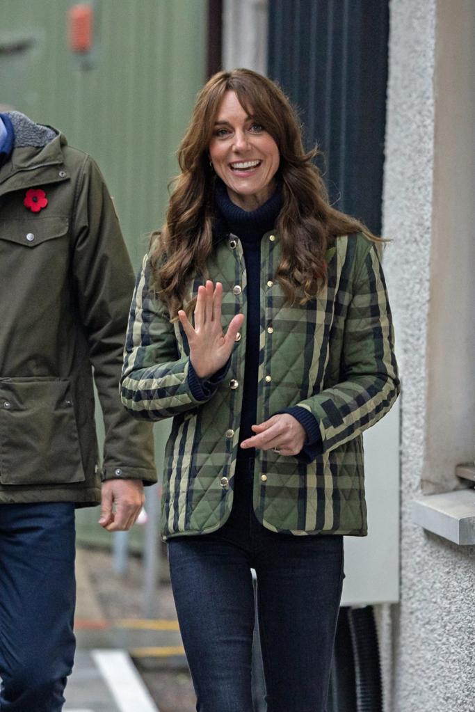 Kate Middleton waves while visiting a charity in Moray, Scotland. She wears a green and black plaid jacket.