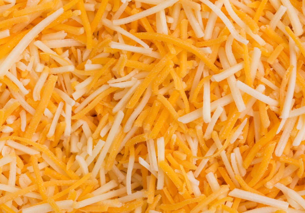 Close view of a shredded white cheddar, sharp cheddar and mild cheddar cheeses