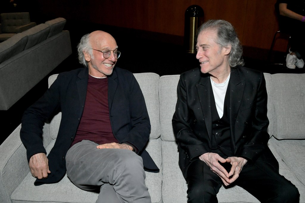 Larry David smiling at Richard Lewis. 