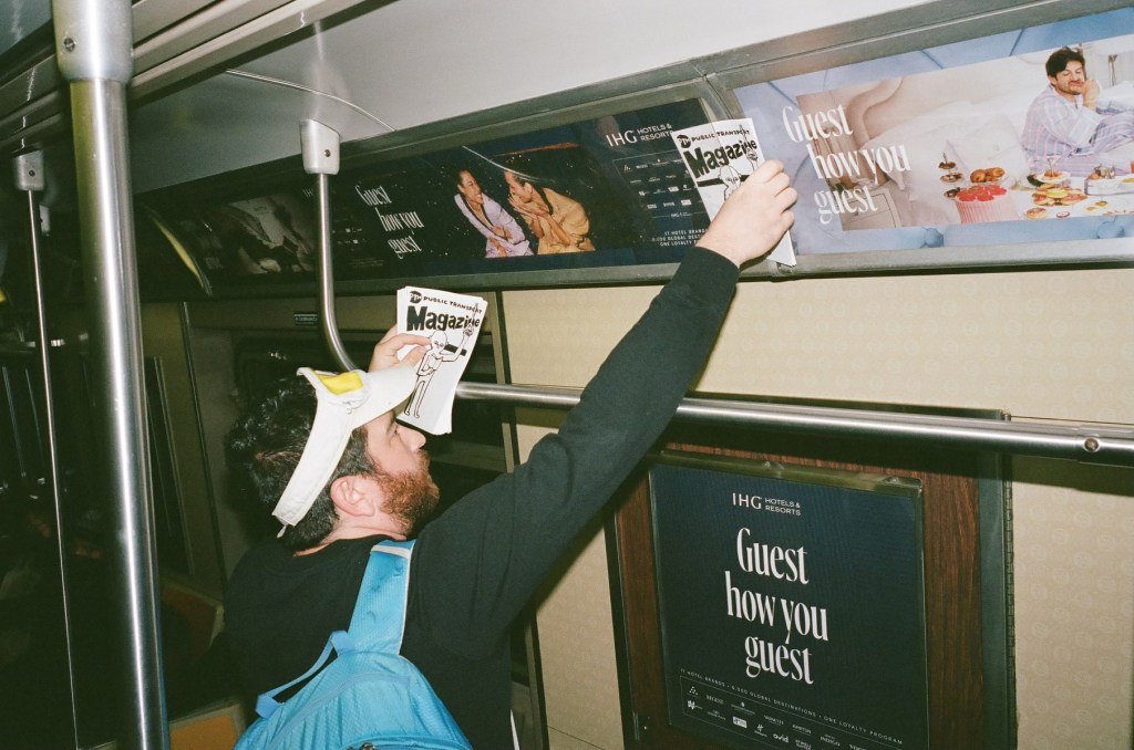 Al Mullen placing a copy of public transport magazine on a subway ad