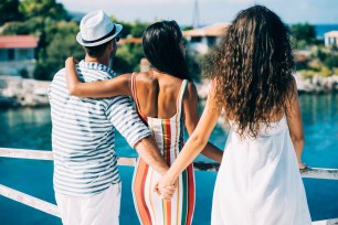 Couple in vacations standing on harbor, man hoding other woman's hand.