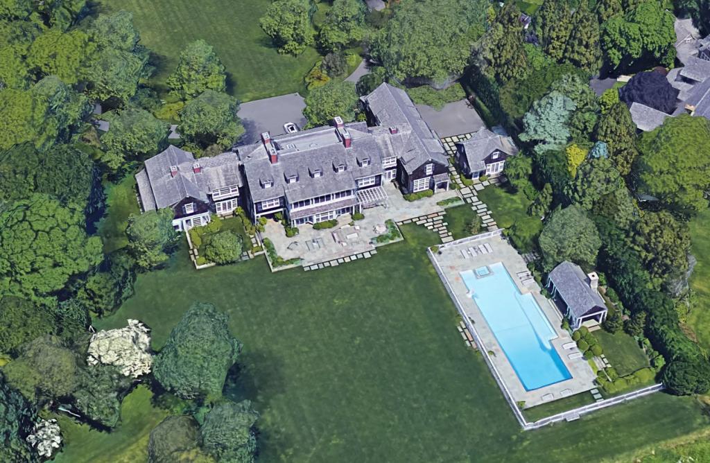 Aerial view of Jerry Seinfeld's large house in East Hampton, NY, featuring a pool and surrounding trees