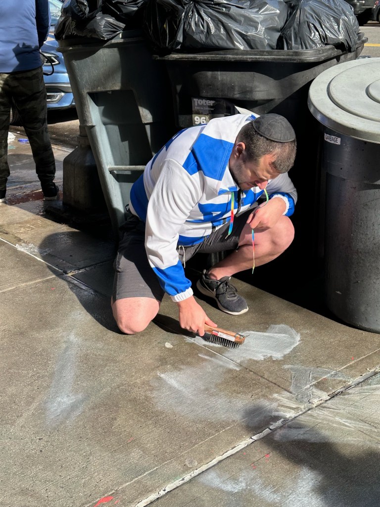 locals stepped in to help scrub the graffiti from the sidewalk.