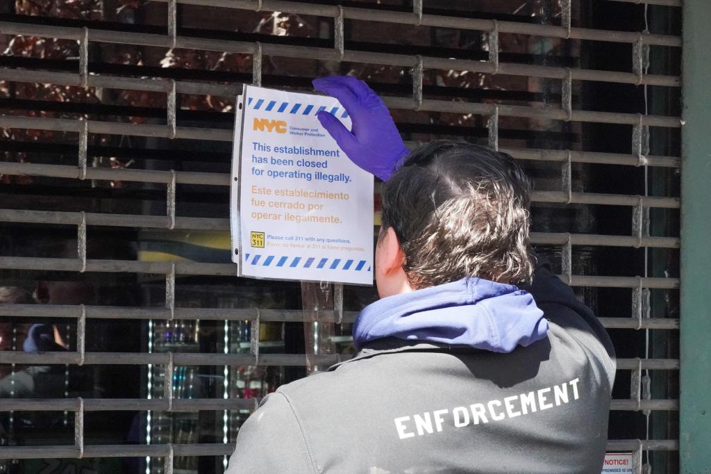 An enforcement official places a sign on a shuttered store after it was closed for illegal operations on March 14, 2024.