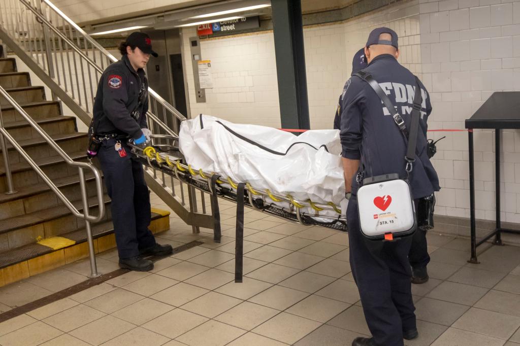 Authorities remove the victim's body from the Harlem subway station