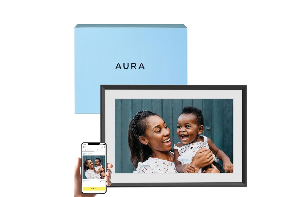 A woman holding a baby and a phone on picture frame