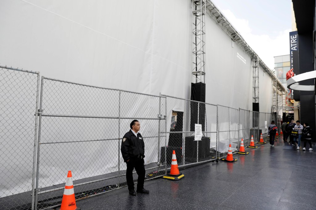 An Academy of Motion Picture Arts and Sciences private security officer stands guard outside the Dolby Theatre.