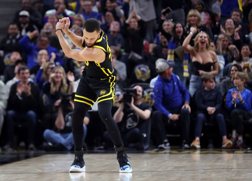 Katherine Taylor celebrates as Steph Curry pretends to hit a golf ball.