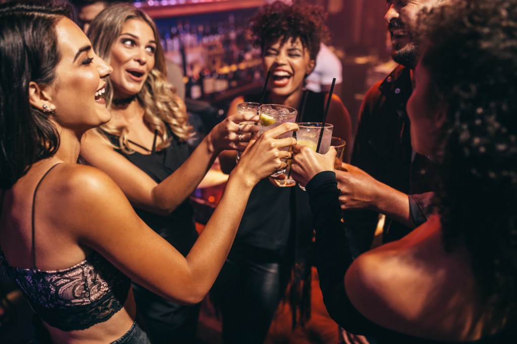 Group of friends toasting drinks in a nightclub. Happy young people with cocktails at pub.