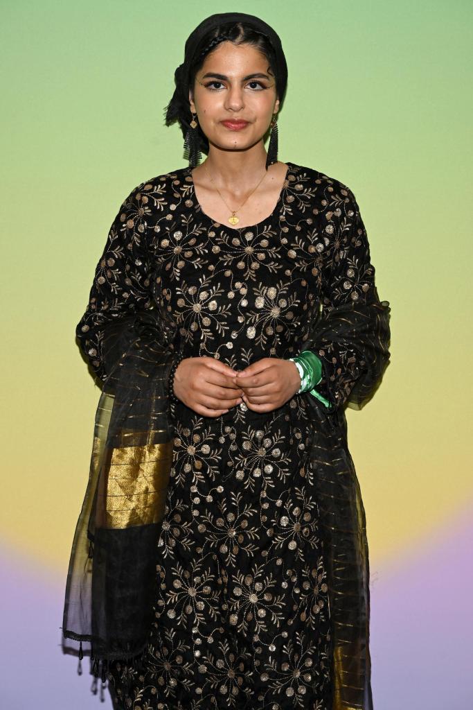 A woman, Ayisha Siddiqa, attends The Meteor & Gucci's summit on gender equity. She wears a black dress. No face is visible.