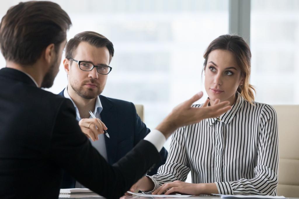 Male job candidate speaking at interview with disapproving recruiters sitting at table, failing recruitment process.