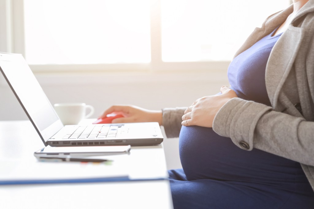 Close up of pregnant woman at a laptop