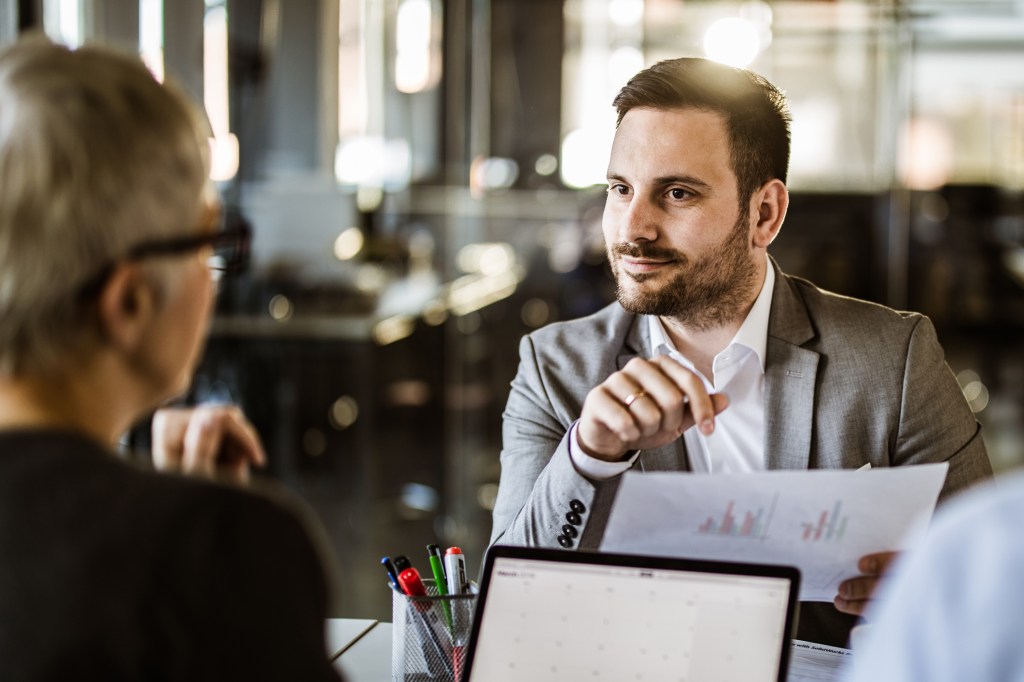 Smiling businessman talking to his colleagues about new reports on a meeting in the office.