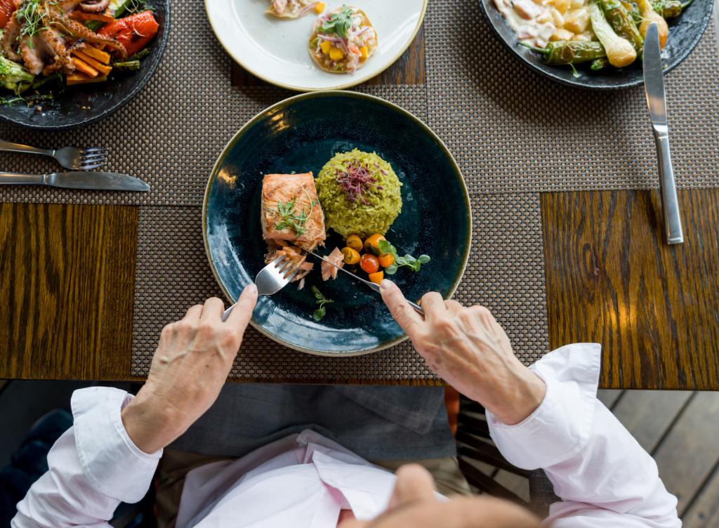 Close-up on a woman eating salmon for dinner at a restaurant.