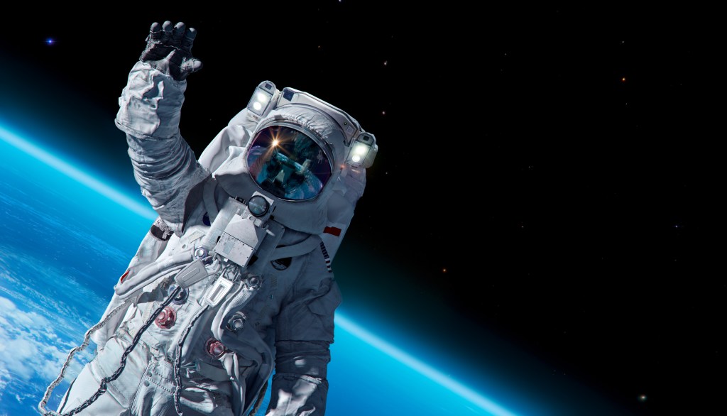 An astronaut in spacesuit against background of the Earth planet. 