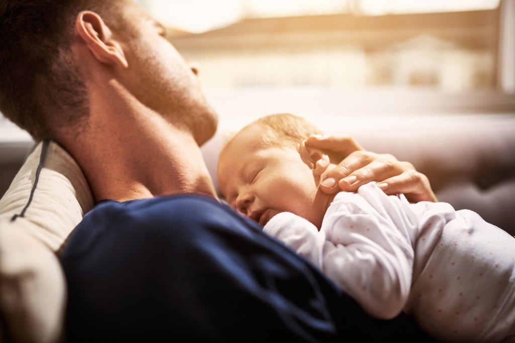 Shot of an adorable baby girl sleeping on her father’s chest at home.