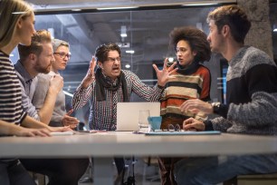 A furious boss shouting at his team in a meeting in office while employees listen.